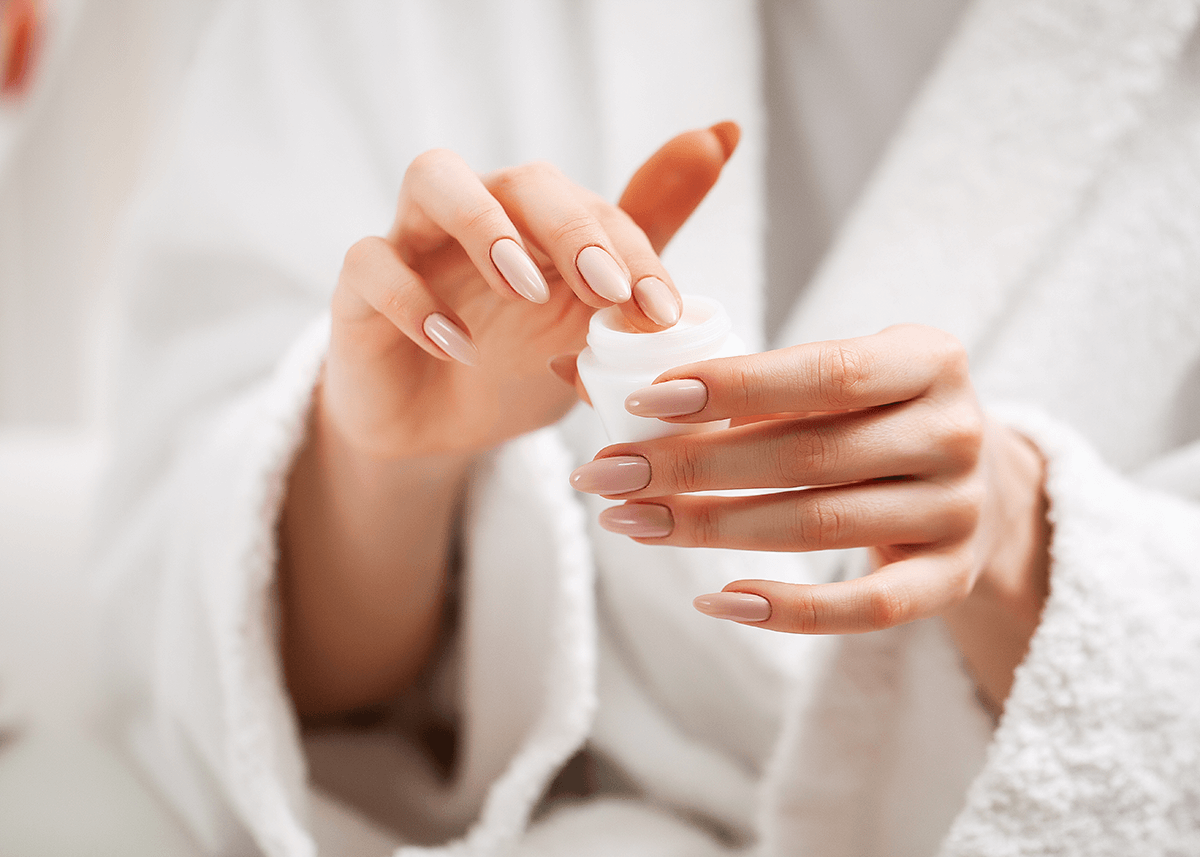 Woman with Nails Applying Moisturizer to Fingers