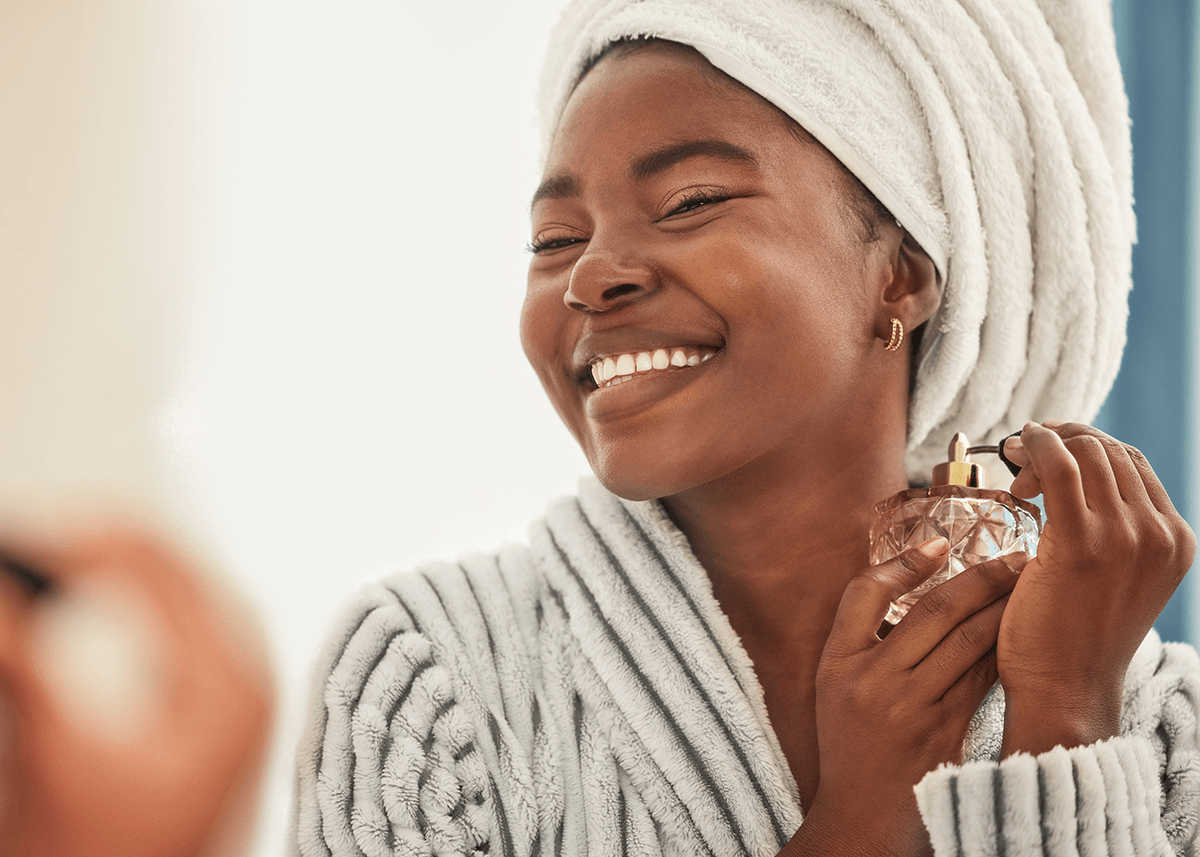 beautiful young african woman spraying perfume after shower