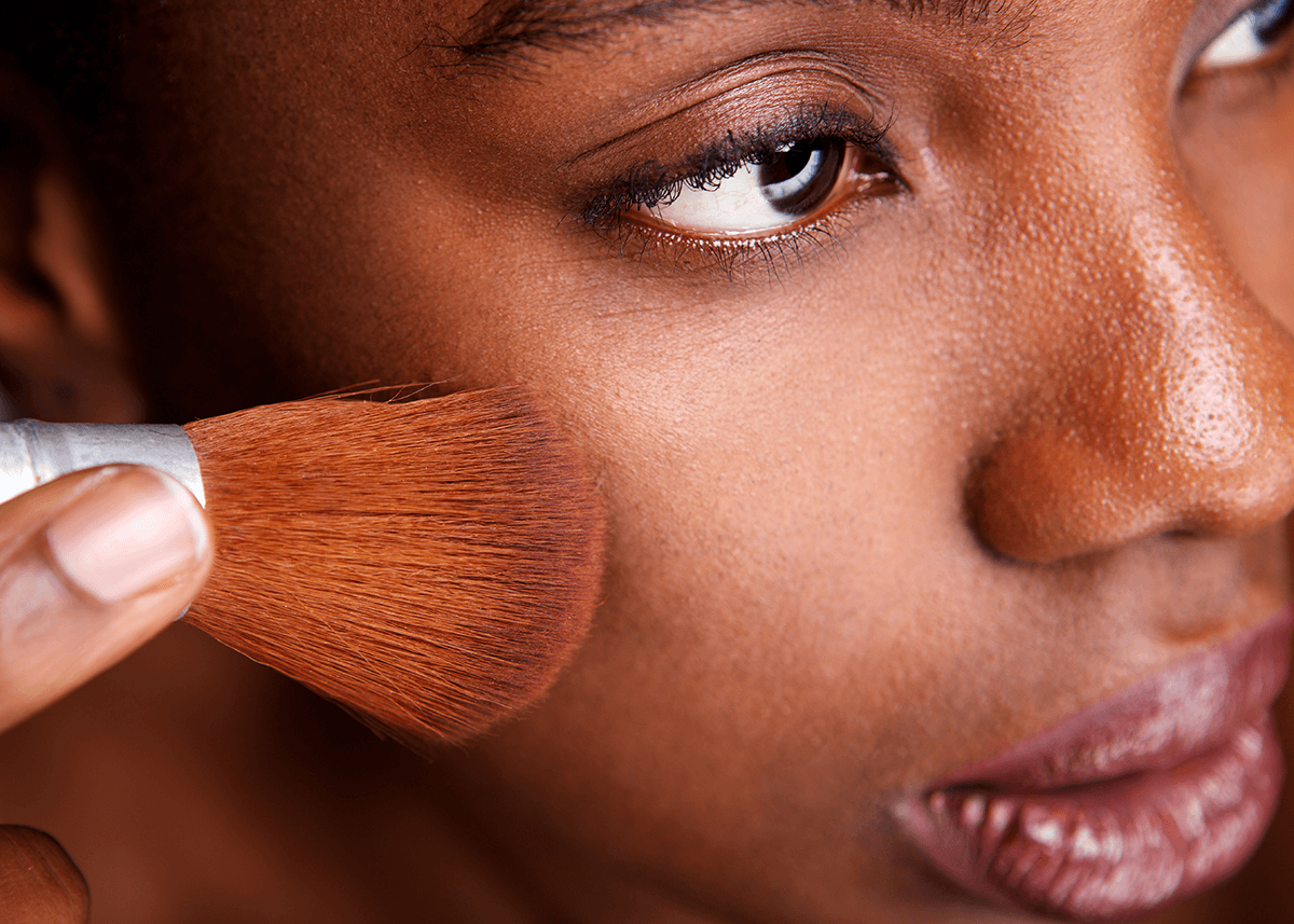 Woman applying makeup with  brush for matte finish