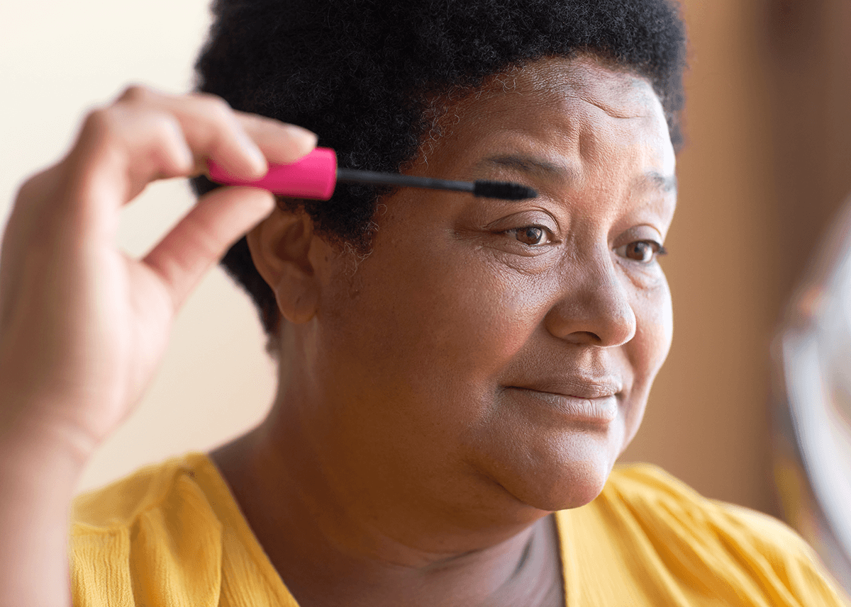 Mature woman applying black mascara on face