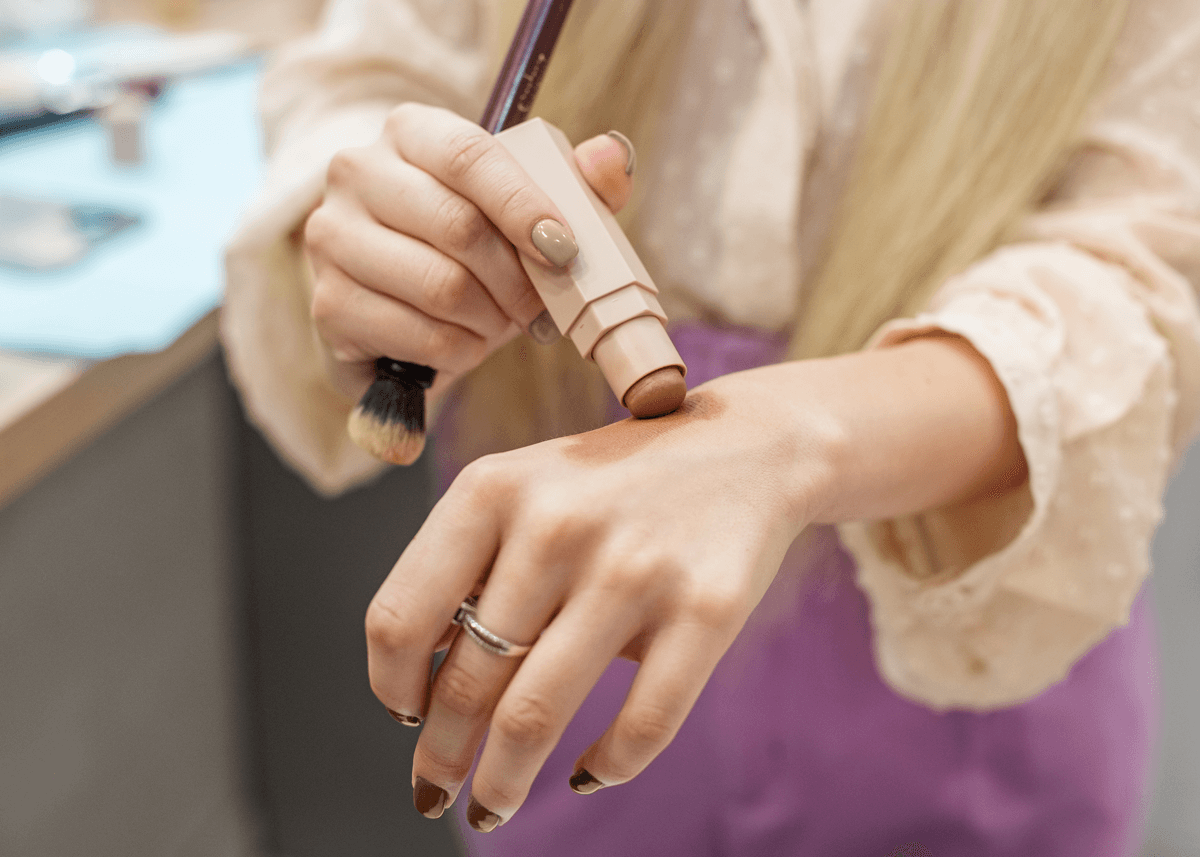 Girl applying bronzer stick to arm