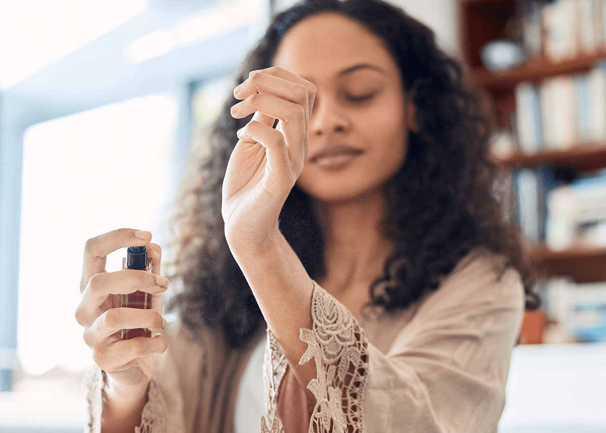 woman spraying perfume on wrists eyes closed