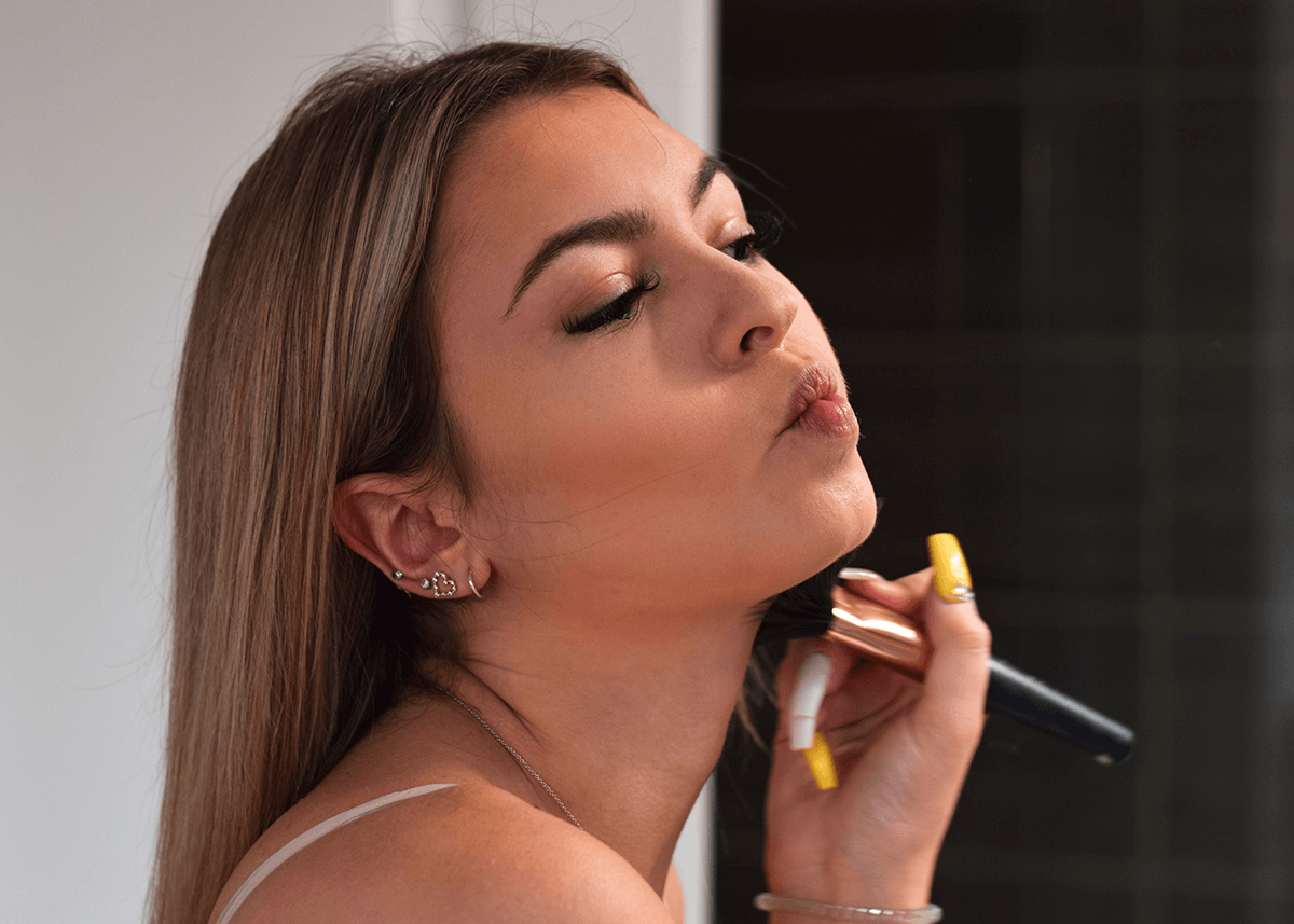 Girl applying bronzer to cheek